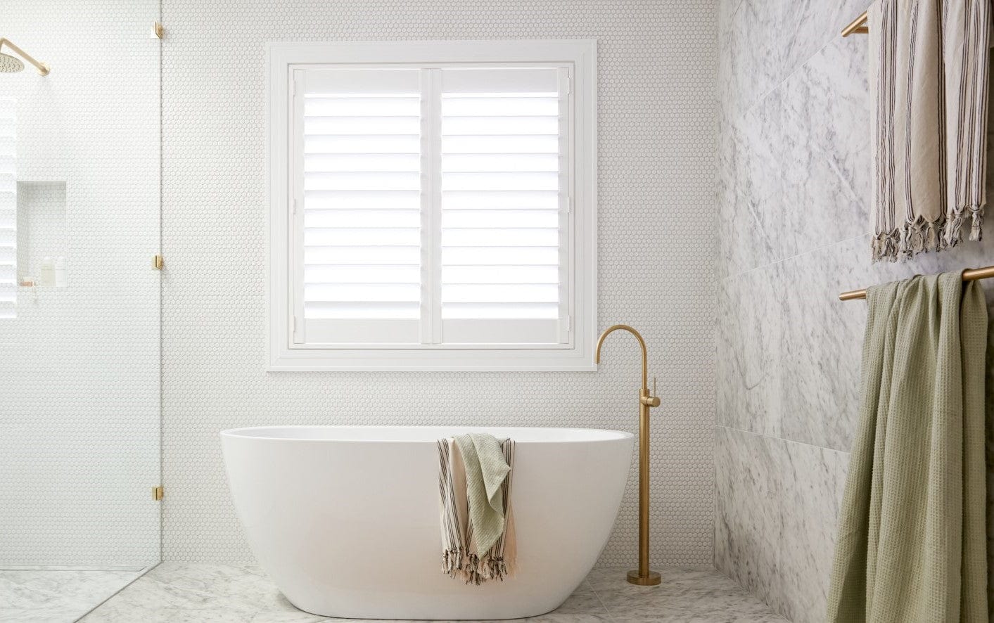 Modern grey and white bathroom with freestanding bathtub and golden faucet.